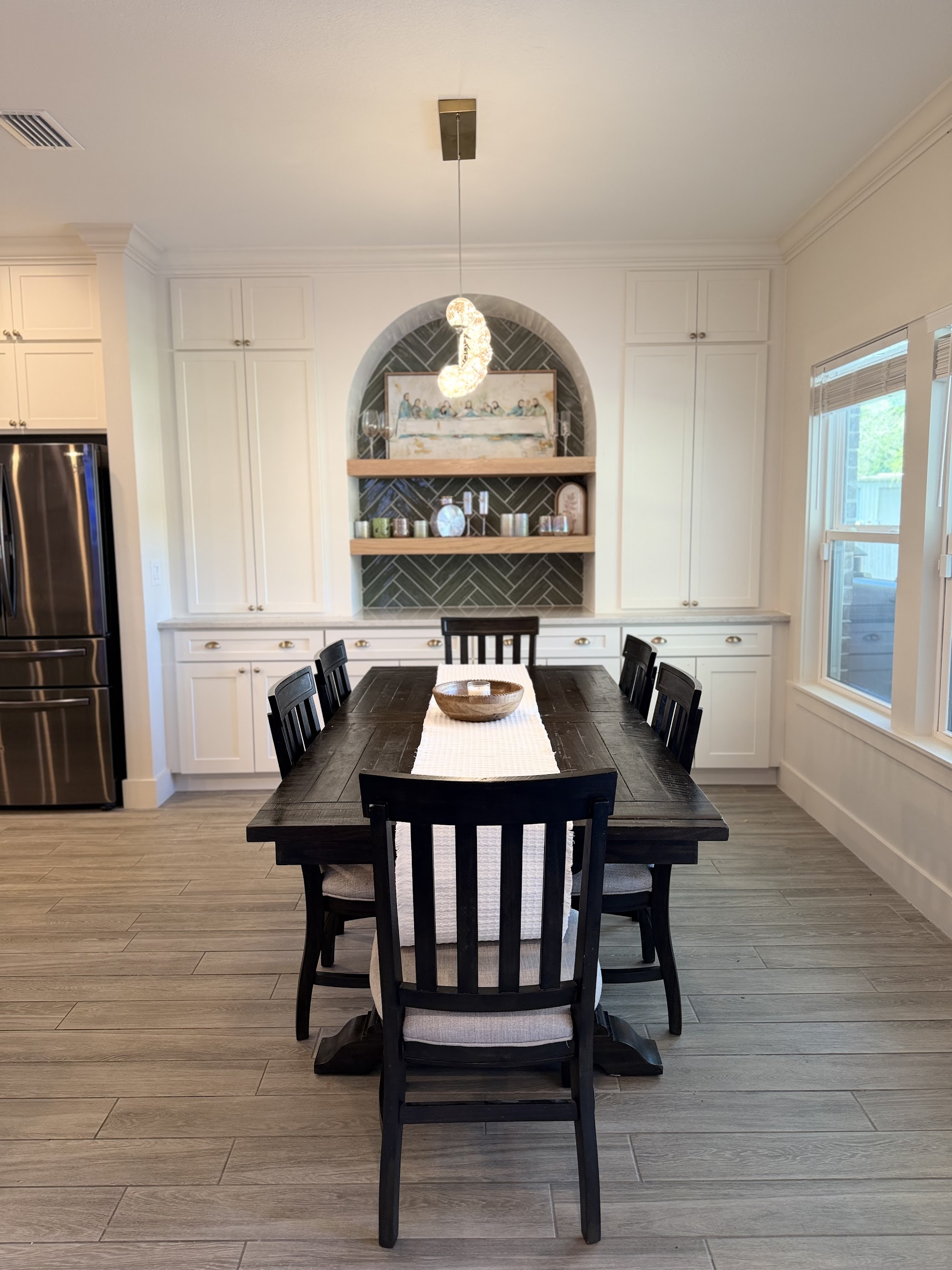 Dining table beside a kitchen with an arched niche and open shelving