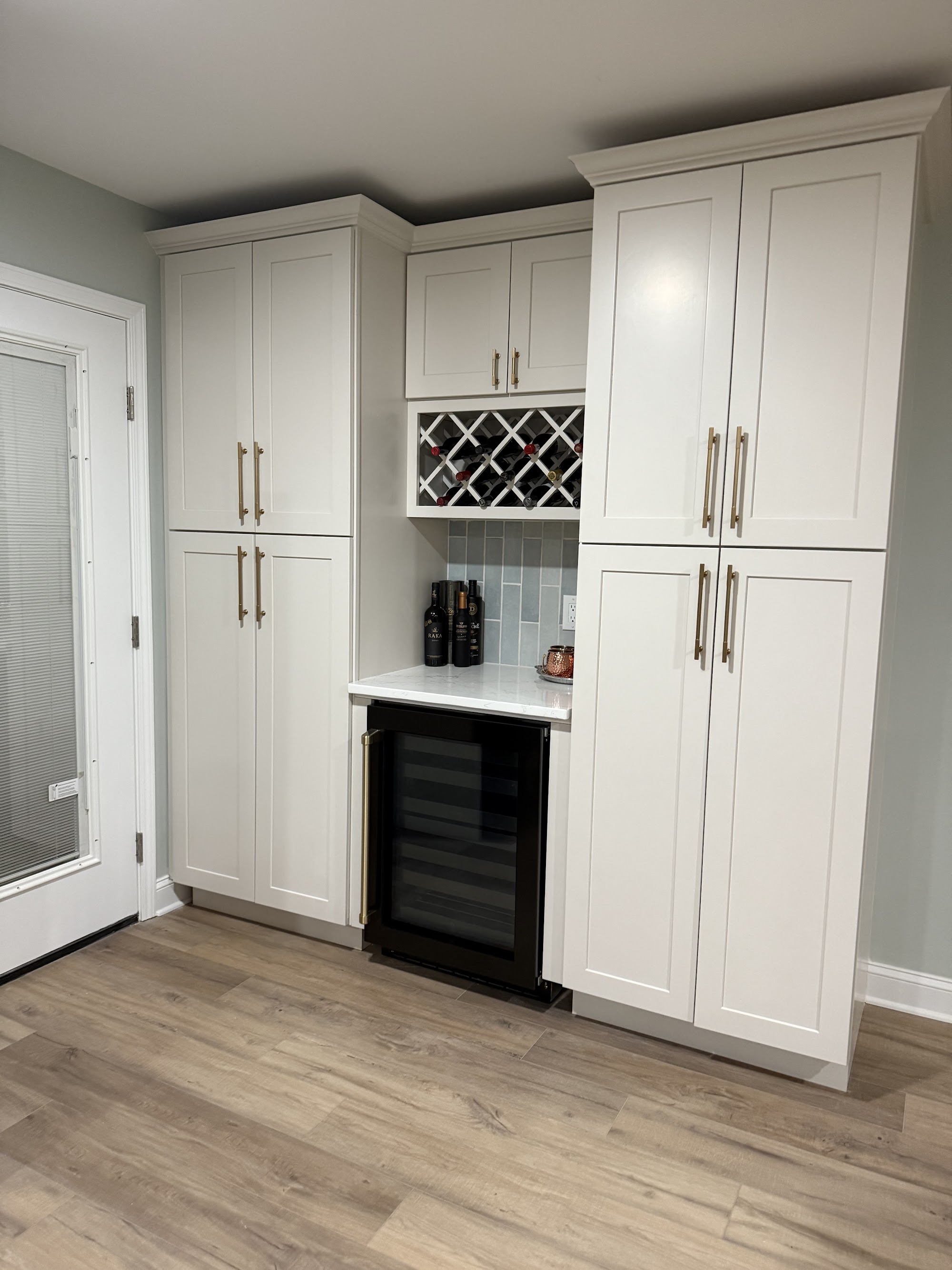 Butler's pantry in white cabinetry with a diamond wine rack, glazed uppers and stone counter