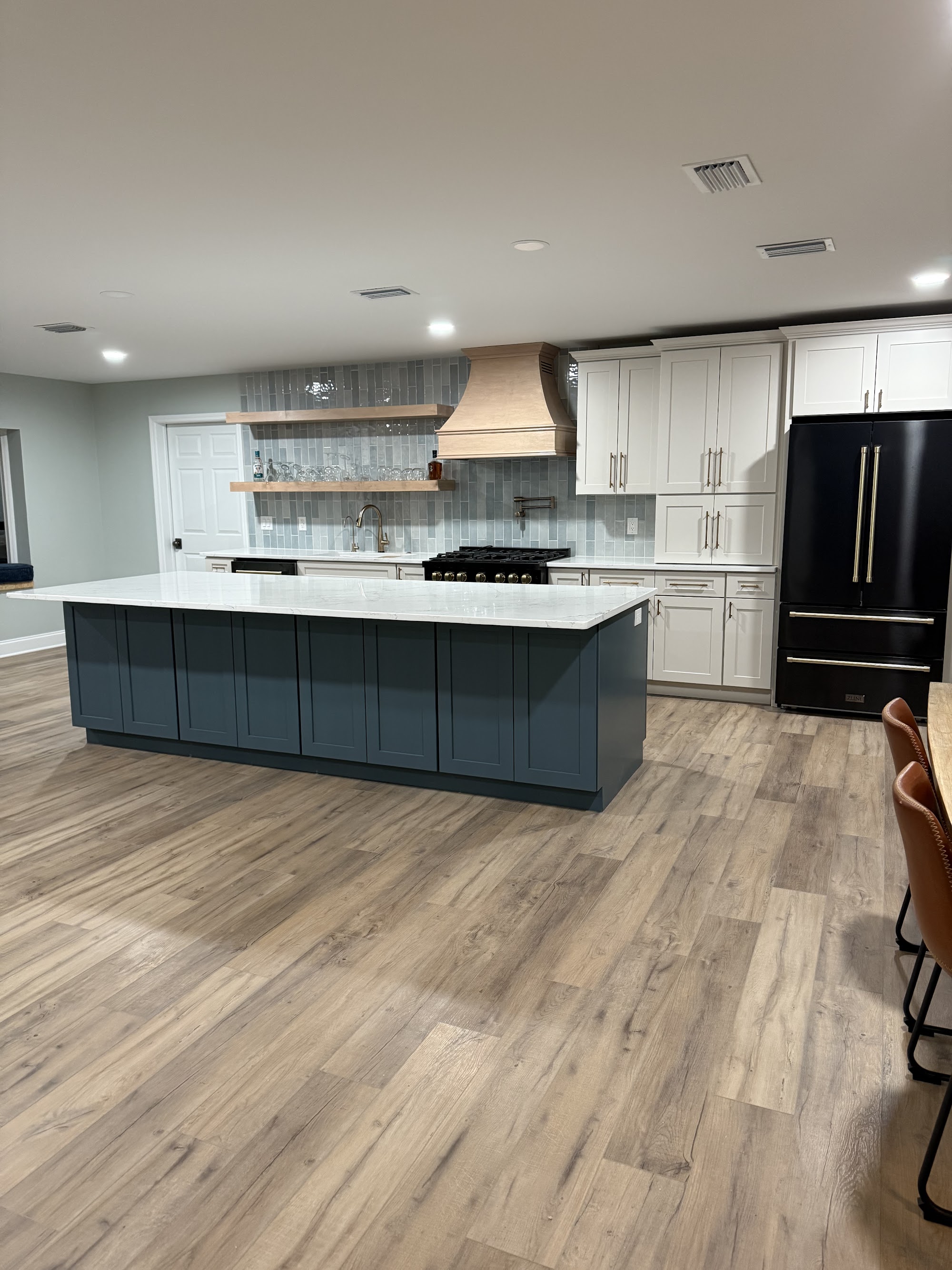 Renovated kitchen with deep blue island, custom hood and open shelving