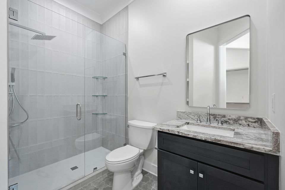 Guest bathroom with a tiled shower over the tub, a dark vanity and a stone counter