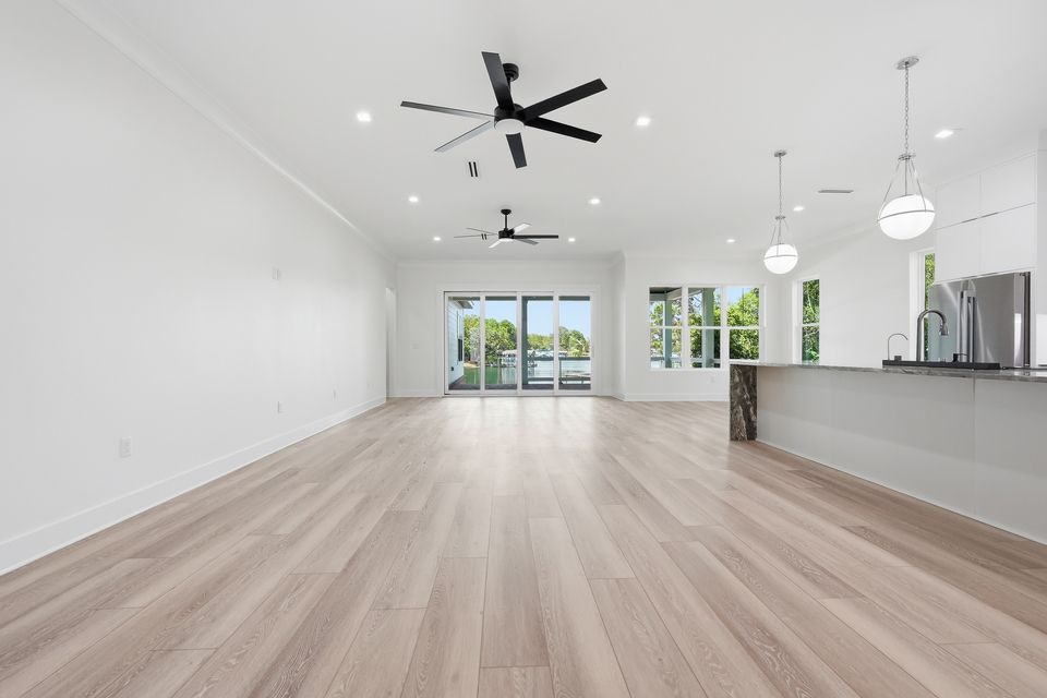 Living room with a vaulted ceiling, wide oak flooring and glazed doors opening toward the water