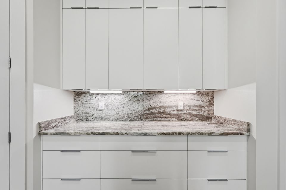 Full-height marble slab backsplash above a run of white cabinetry with brushed hardware