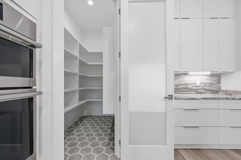 Walk-in pantry with open shelving and a hexagon tile floor seen through a glazed door