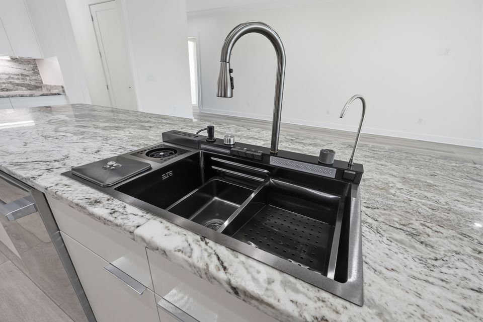 Undermount sink in a veined stone counter with a matte black gooseneck tap and pot filler